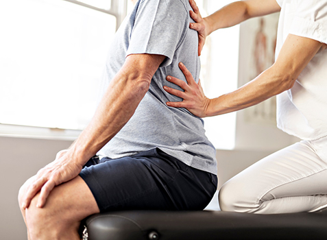 Care provider assessing patient’s back during Muscle Energy Treatment session