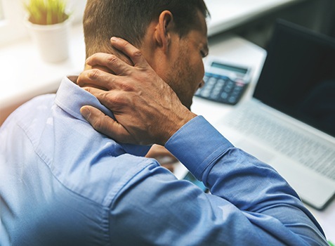 Businessman holding the back of his neck in pain
