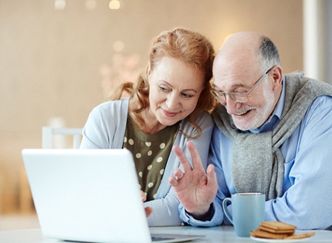 Senior couple smiling at computer during telemedicine call