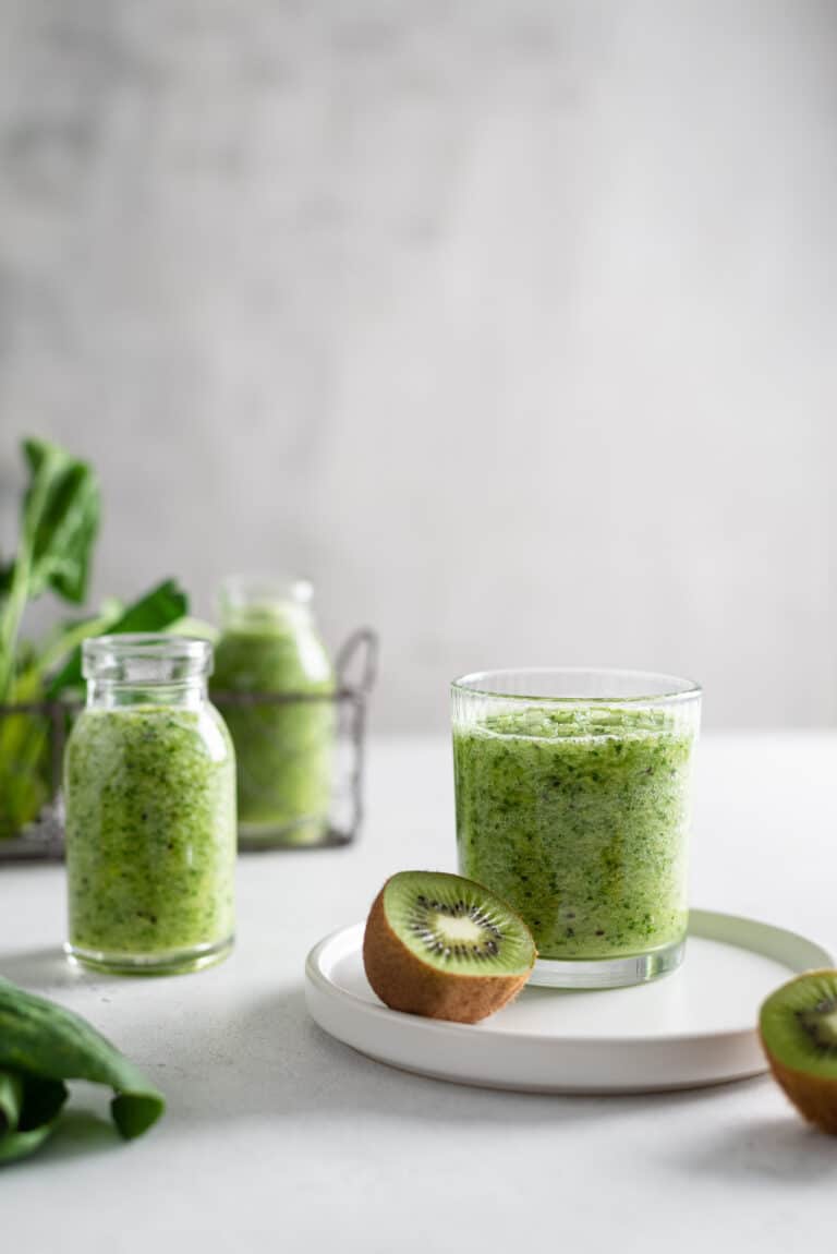 Healthy detox green smoothie with spinach, apple and kiwi in a glass with fresh ingredients on light background. Copy space, side view. Detox menu, dieting, healthy nutrition.