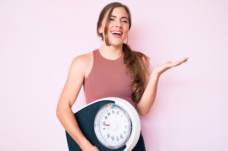 Happy woman carrying bathroom scale