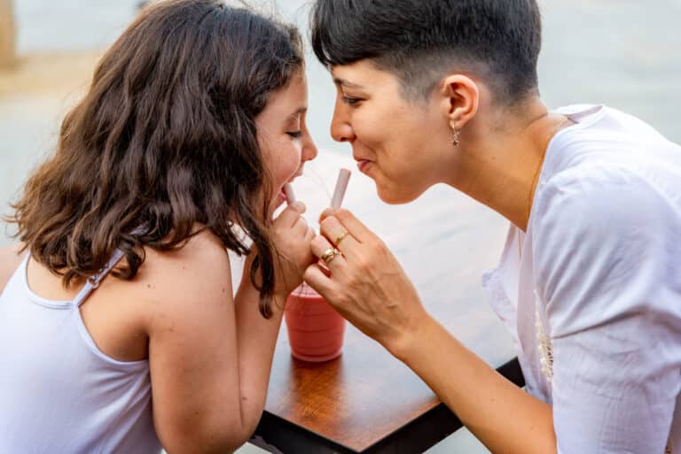 Mother and daughter having fun drinking milkshake